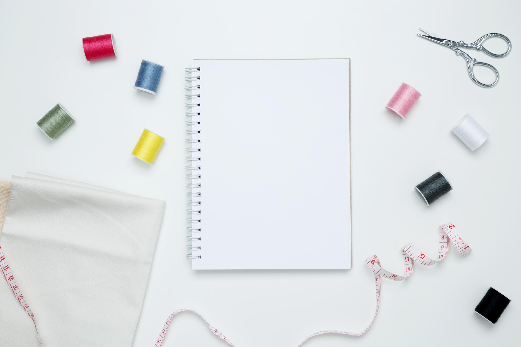 Flatlay of embroidery tools and notebook